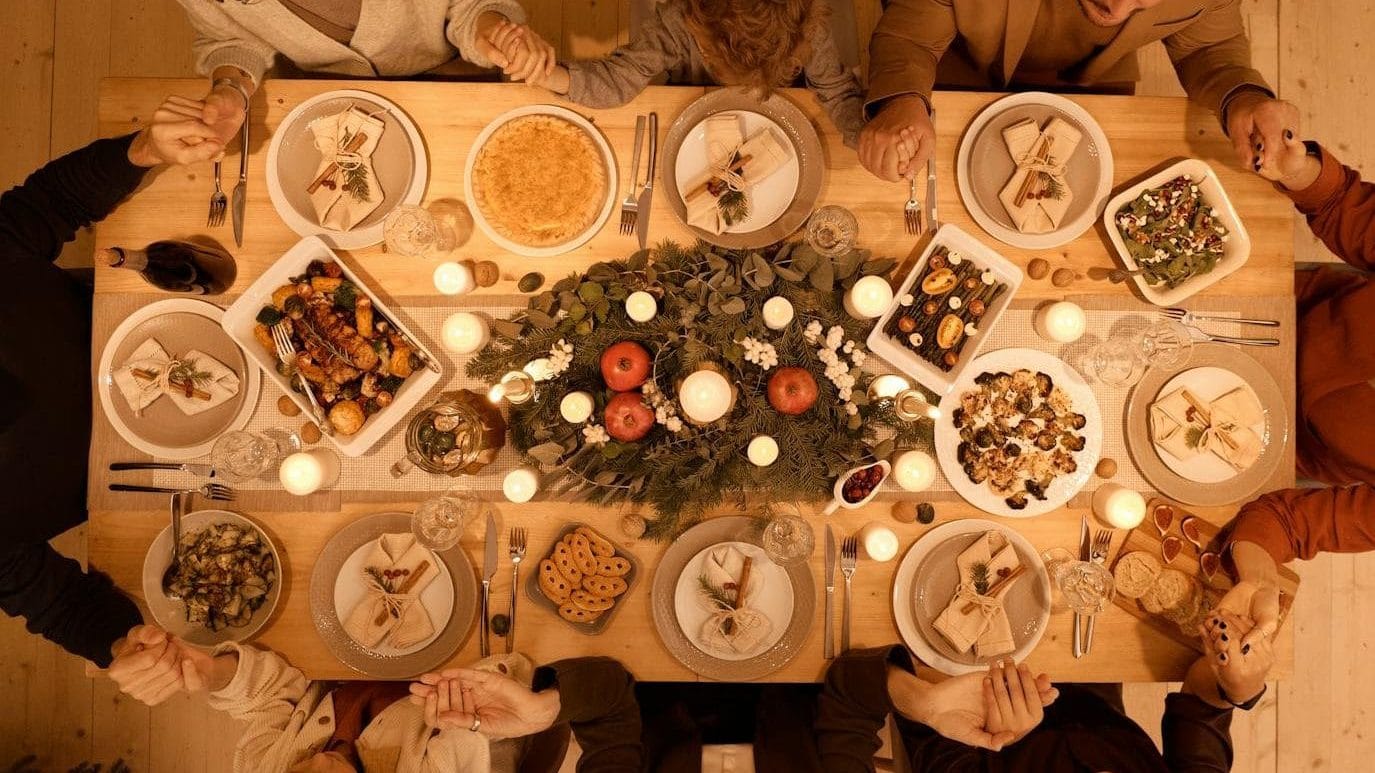 Family gathered around a beautifully set table for a festive Christmas dinner celebration. Generous table, hospitality