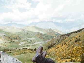 person wearing brown leather boots near mountains at daytime